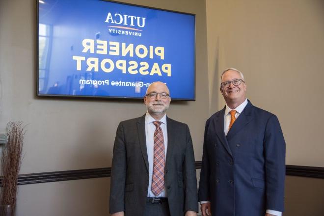 President Todd Pfannestiel and VP of Enrollment Management Eric Sykes stand in front of monitors announcing 先锋的护照.